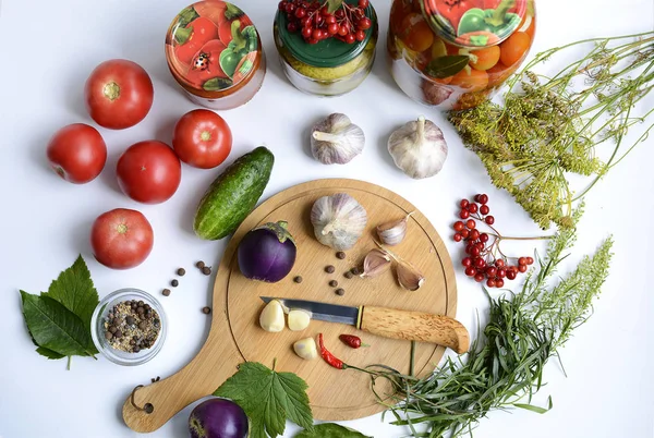 Vista superior de una tabla de cortar con un cuchillo, rodajas de ajo, berenjena y pimiento picante, así como tomates, pepinos, especias y hierbas — Foto de Stock