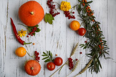 Circular pattern of red, yellow, orange vegetables and berries on a light wooden table