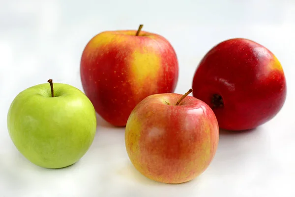 Trois pommes rouges et une pomme verte sur fond blanc, gros plan — Photo