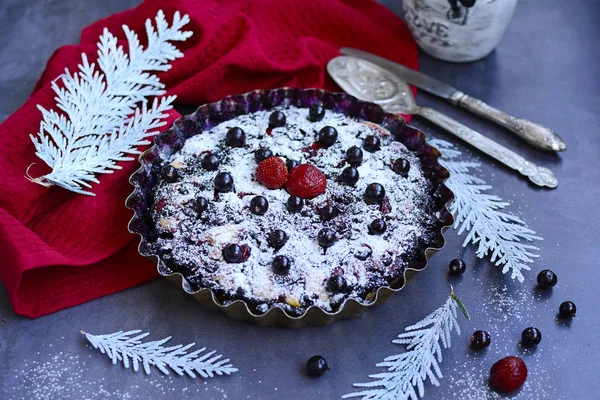 Домашній пиріг чорної смородини, посипаний глазурованим цукром у випічці, червона серветка та полуниця на сірому столі . — стокове фото
