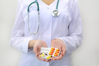 Beyaz bir arka planda ellerinde haplar ve kapsüllerle doktorun elleri. Tedavi konsepti. Kapat.