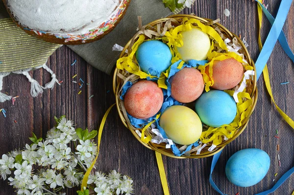 Uova di Pasqua multicolori in un nido su uno sfondo di legno rustico — Foto Stock