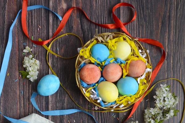 Uova di Pasqua colorate in nido su sfondo marrone in legno . — Foto Stock