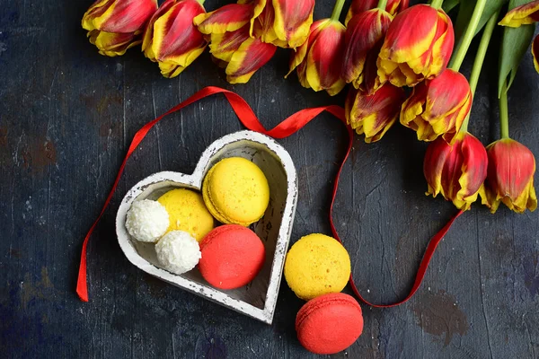 Composition festive de macarons rouges et jaunes dans une boîte en bois et de tulipes sur un fond sombre. Vue d'en haut — Photo