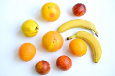 Portakallar, greyfurtlar, kırmızı portakallar, muz ve ayva beyaz arka planda, üst manzara. C vitamini.