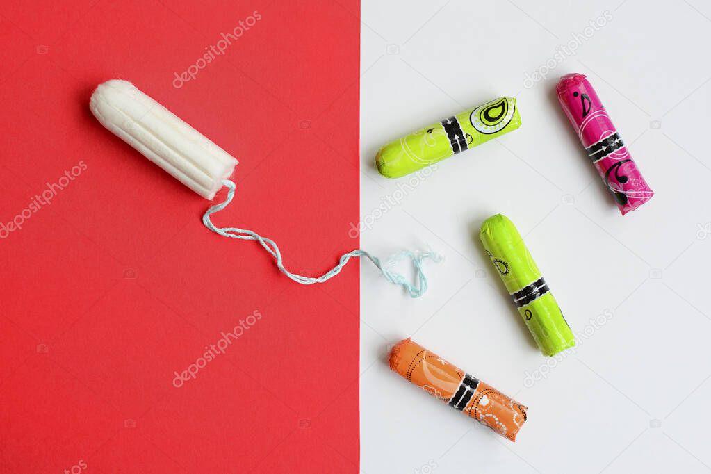 Top view of a cotton swab on a red background and multi-colored swabs in a package on a white background. Protection of feminine hygiene during menstruation