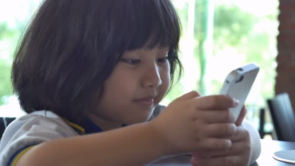 4k: közelről ázsiai gyermek játszani a játékot a szúró telefon együtt — Stock videók
