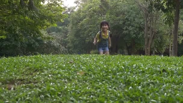 Colpo al rallentatore: Felice bambina asiatica che corre nel parco con la luce del sole — Video Stock