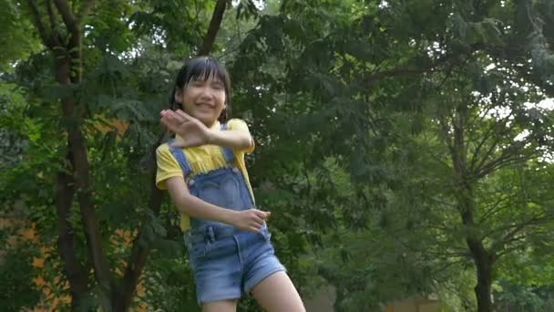 Снимок замедленного действия: счастливая азиатская девочка поет и танцует в парке — стоковое видео