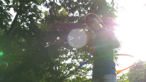 Slow motion shot : Happy Asian little girl playing colorful holahoop in the park with sun light — Stock Video