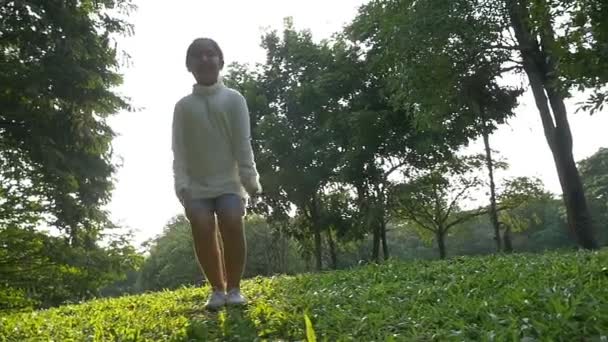 Slow motion shot: Happy asiatiska liten flicka hoppa i parken med solljus — Stockvideo