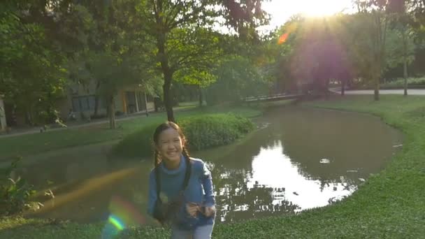 Снимок замедленного действия: счастливая азиатская девочка бегает в парке с солнечным светом — стоковое видео