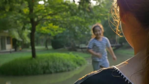 Mooi Aziatisch meisje loopt naar haar moeder, die haar knuffels met genegenheid, Slow motion shot — Stockvideo