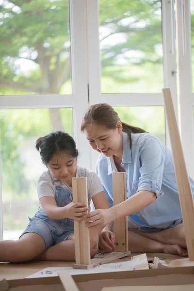 Asiatisk härlig flicka att hjälpa mamman montering nya Diy möbler hemma tillsammans — Stockfoto