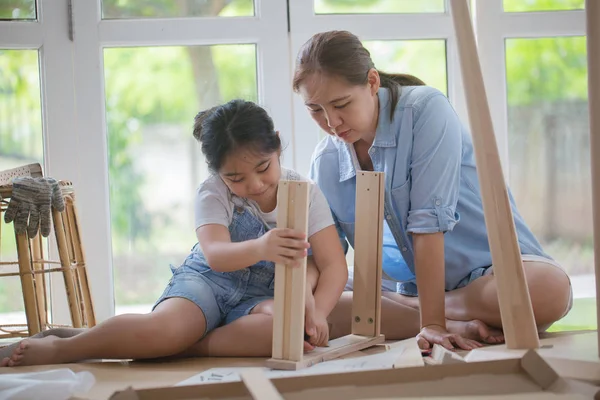 Asiatisk härlig flicka att hjälpa mamman montering nya Diy möbler hemma tillsammans — Stockfoto