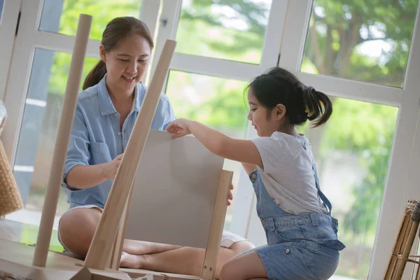 Asian lovely girl helping her mother assembling new DIY furniture at home together — Stock Photo, Image