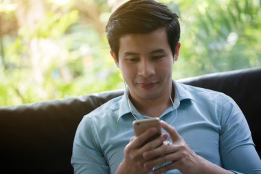Küçük Asya adam dinleme müzik akıllı telefon Cafe