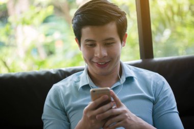Küçük Asya adam dinleme müzik akıllı telefon Cafe