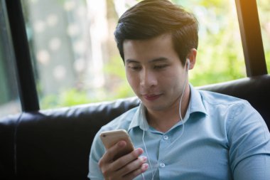 Küçük Asya adam dinleme müzik akıllı telefon Cafe