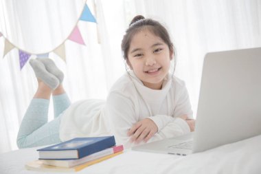 Asyalı kız yatak odasında dizüstü kullanarak pastel üçgen parti bayrağı ile süsleyin