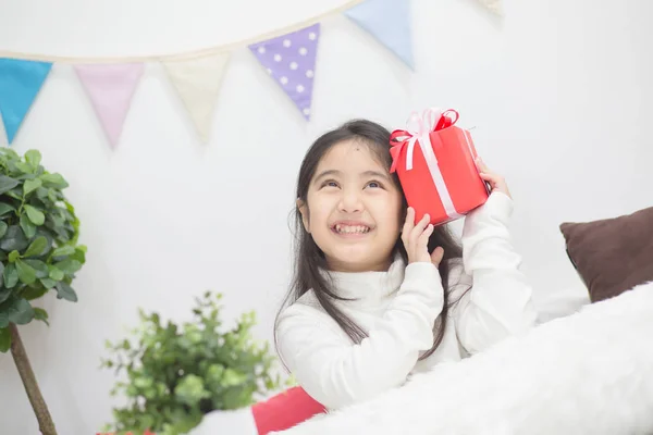 Glücklich asiatische Mädchen schütteln ein Geschenk zu erraten, was drinnen — Stockfoto