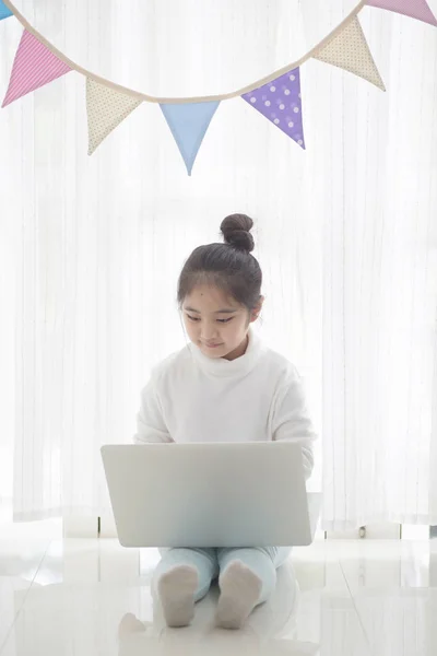 Glad flicka använder laptop i rum inredda med pastellfärgade triangel partifana, hög nyckelprocess — Stockfoto