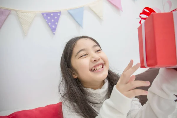 Happy Asian girl shaking a present to guess whats inside — Stock Photo, Image