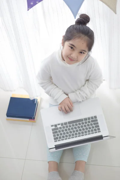 Asiatisk tjej med laptop i sovrum dekorera med pastellfärgade triangel partifana — Stockfoto