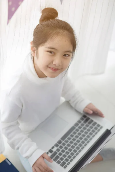 Asiatique fille à l'aide d'un ordinateur portable dans la chambre à coucher décorer avec drapeau parti triangle pastel — Photo