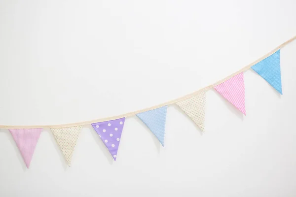 Kleurrijke partij vlaggen bunting hangend aan witte muur voor vakantie decoratie — Stockfoto