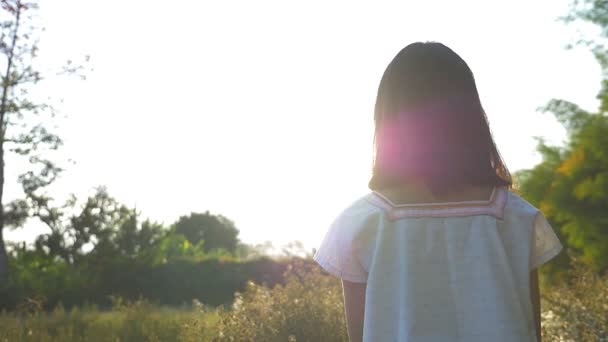Rallentatore colpo di felice asiatico ragazza a piedi in il fiore campo con sole — Video Stock