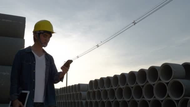 4k: asijské inženýr pomocí mobilního telefonu na staveništi s modrou oblohou — Stock video
