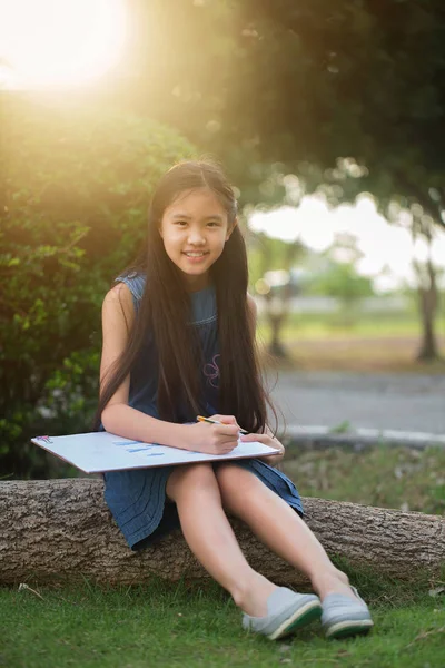 Heureuse fille asiatique profiter de dessiner des photos dans le parc — Photo