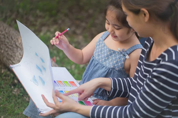 Filha asiática feliz desenho quadro com a mãe juntos no parque — Fotografia de Stock