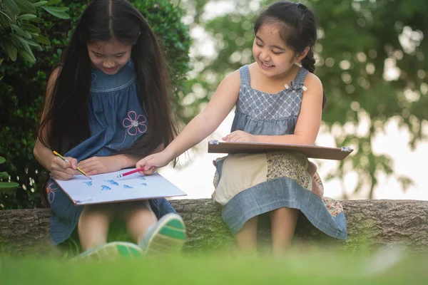 Heureuses filles asiatiques appréciant de dessiner des photos ensemble dans le parc — Photo
