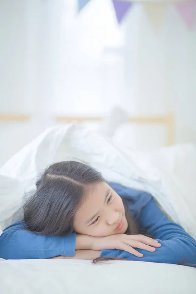 Ευτυχισμένος κορίτσι της Ασίας ξαπλωμένη στο κρεβάτι με το φως του ήλιου την ημέρα τεμπέλης — Φωτογραφία Αρχείου