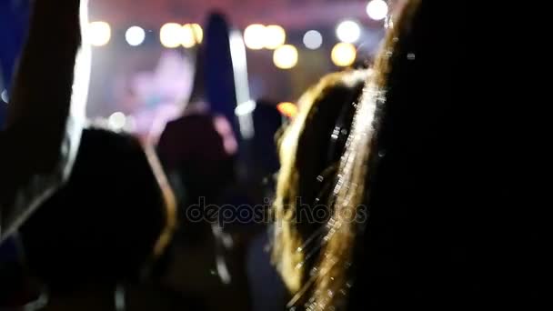 Siluetas borrosas de la multitud de conciertos frente a luces de escenario brillantes en Asia, disparo en cámara lenta — Vídeo de stock