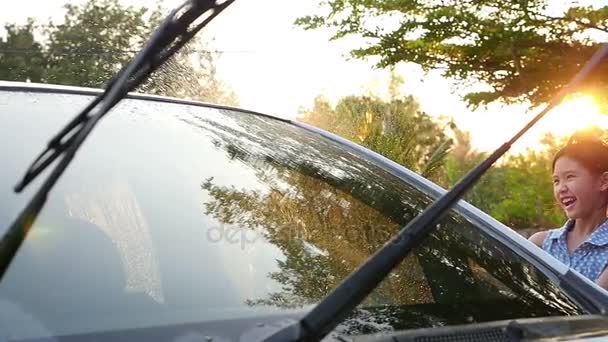 Feliz chica asiática lavando coche en el agua salpicaduras y la luz del sol en casa: Lento tiro en cámara — Vídeo de stock