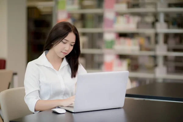 Portrait d'une belle étudiante asiatique heureuse utilisant un ordinateur portable dans une bibliothèque — Photo