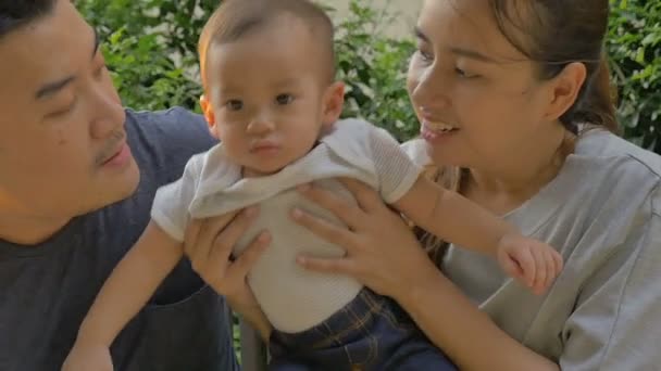 Câmera lenta de feliz bebê asiático com sua mãe e pai brincando juntos no parque — Vídeo de Stock