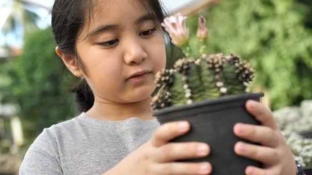 4К Медленное движение симпатичной маленькой азиатской фермерской девочки посадки различных кактусов на ферме — стоковое видео
