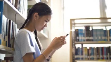 4 k Asya öğrenci ateş doğal ışık, ağır çekim için ilham, okul Kütüphanesi olarak akıllı telefon kullanarak