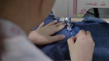 Asyalı kadın ellerini kapat atölyede dikiş makinesiyle elbise dik
