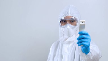 Kızılötesi termometreyle tarama yapan sağlık çalışanı, kızılötesi termometreyle, koruyucu PPE kostümlü ve gözlüklü kendine güvenen Asyalı doktor.