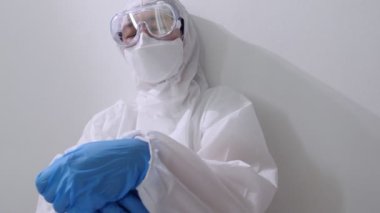 PPE takım elbiseli Asyalı bir doktor yerde oturup uyumaya çalıştı, ağır çekimde çok çalışan bir doktor.