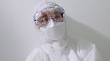 PPE takım elbiseli Asyalı bir doktor yerde oturup uyumaya çalıştı, ağır çekimde çok çalışan bir doktor.