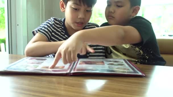 Happy asian child look and choose in menu book. — Stock Video