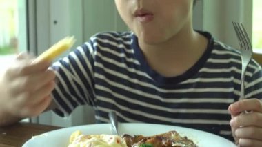 küçük Asyalı çocuk gülümsemek yüz ile restoranda sebze salatası ile Biftek yerken