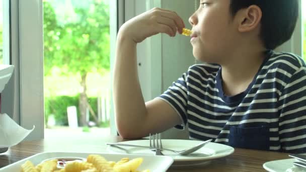 小亚洲男孩满脸微笑的餐厅吃牛排配蔬菜沙拉 — 图库视频影像