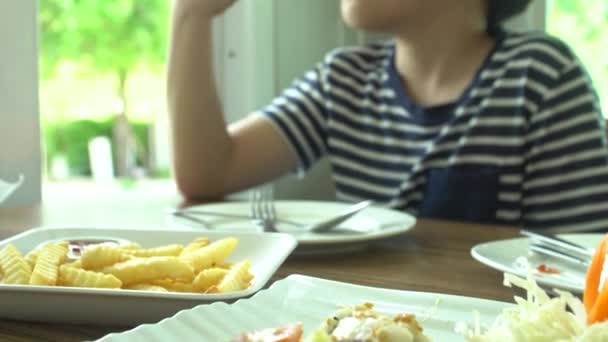 Menino asiático comendo bife com legumes Salada no restaurante com rosto de sorriso — Vídeo de Stock